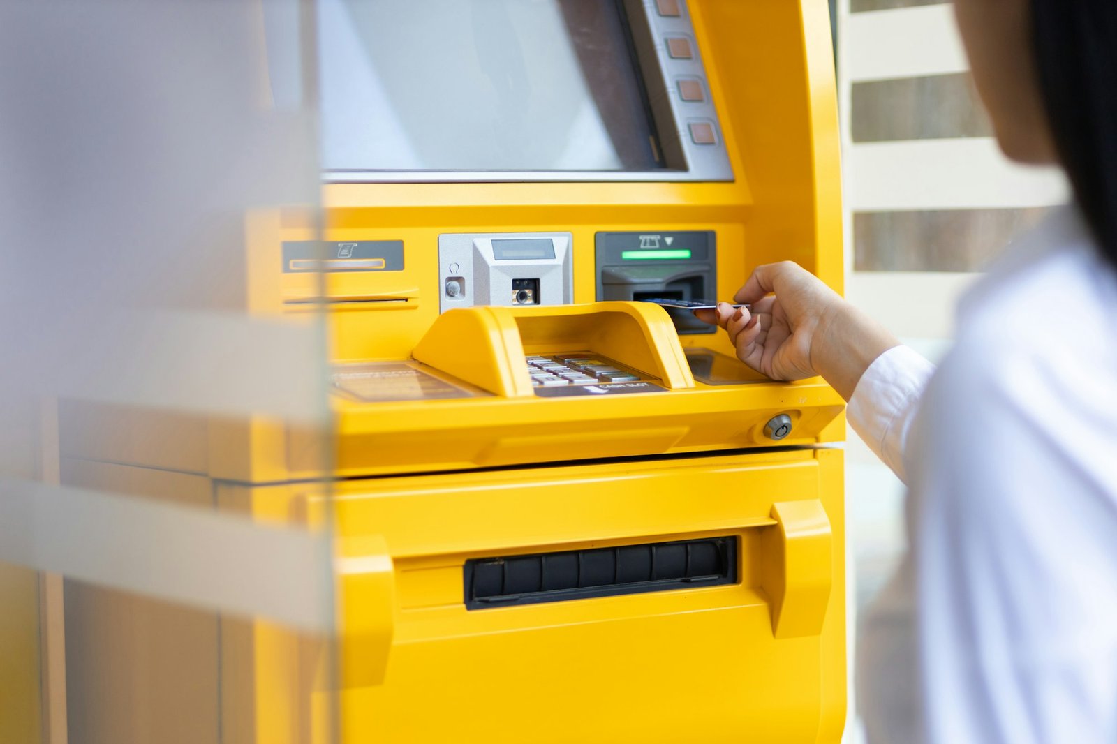 Woman at ATM using cash card in cash machine to pay for shopping.